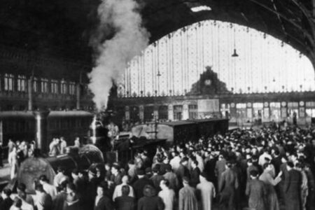 Estación de Atocha antigua con tren de vapor y multitud de pasajeros bajo la marquesina histórica en Madrid