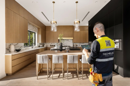 Técnico de TECMELEC configurando un sistema avanzado de automatización inteligente mediante tablet en una cocina moderna de lujo